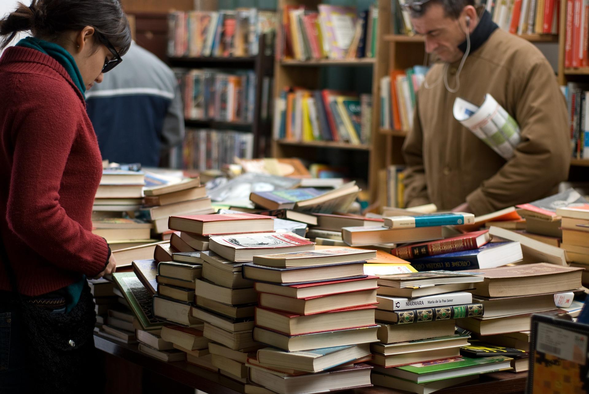 A man and woman browsing the stacks of books laid out on display at the book sale
