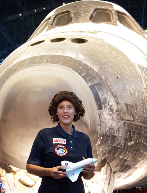 Image of living history actress as Sally Ride standing in front of large space shuttle