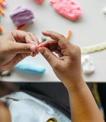 child's hands manipulating a small piece of playdough