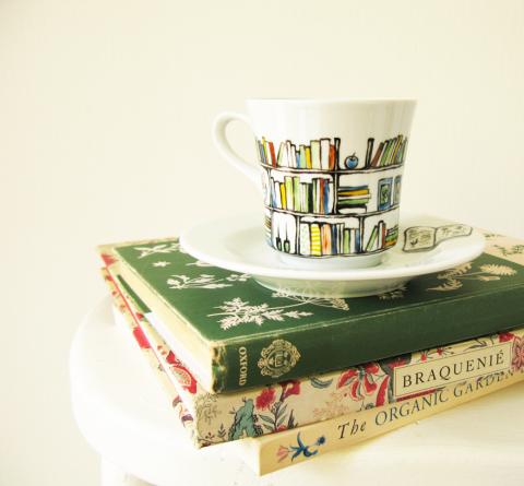 Tea cup with book shelf design on top of small stack of books