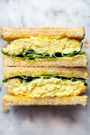 two halves of an egg salad sandwich next to each other