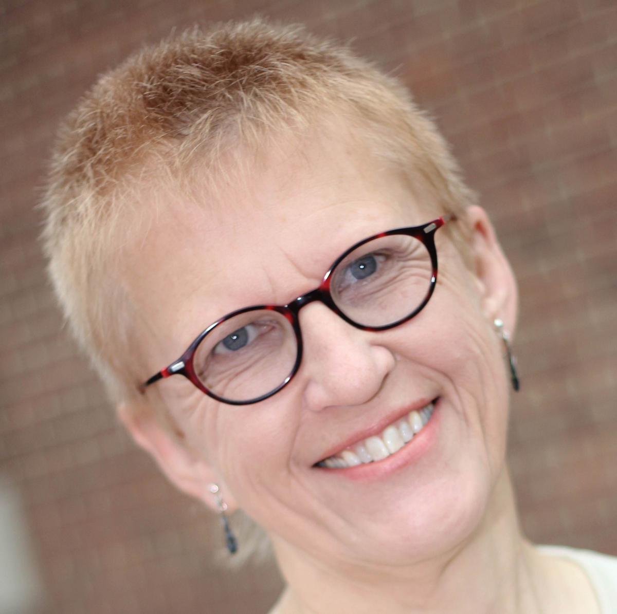 Photograph of Barbara Irvine, with glasses, smiling.